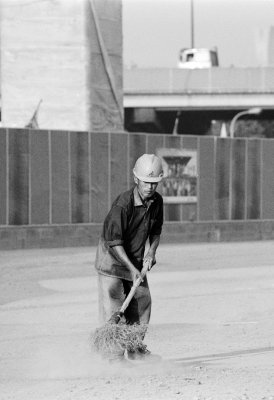 A worker sweeps the road along the construction site of the maglev from Shanghai to Beijing. An old fashioned broom seems little help against the engulfing dust at the end of a long summer in Shanghai on this early morning.