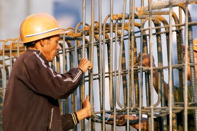 Two workers are bending new steel together in the early morning sun on a construction site in Shanghai. Overhead, the maglev train, and several highways crisscross and branch.

I was fortunate to be there on an early Sunday morning, with the site open and people friendly and welcoming again.