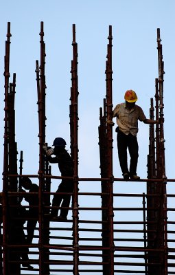 Hard at work in the scaffolds, workers appear as black outlines against the morning sky. Only one is lit enough to make out the details and colors of his clothes.

I was lucky to get just enough light on him, with the others mostly dark, to make this shot work well.