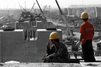 From atop an almost finished pillar, two workers gaze out as the construction site stretches out into the distance of Shanghai. On the left, the big new station will arise. Meanwhile, the workers still have a long way to go to connect Shanghai and Beijing.