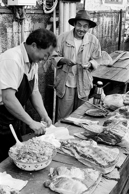 On a market in Heshun, a man in hat with really funny teeth smiles at into the camera, while the butcher cuts his meat for him.

The setting was just too funny and the smile to engaging to pass up.

The meat on the market has, like nearly everywhere else, never seen the inside of a cooler or fridge. Fortunately it is ont too hot, this high up in the mountains.