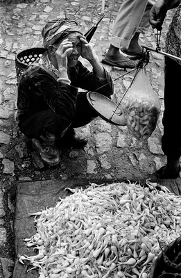 Out West in Yunnan, close to Ruili, near the border with Myanmar, an old woman haggles over the price for a bag full of vegetables. Her drawn face shows just how bitter her days have become, and many people in this area are not much better off. 

The market itself is a ramshackle affair for local villagers, with the raw meat under the sun attracting it's share of flies and the severed head of a pig a bargain not be be passed.