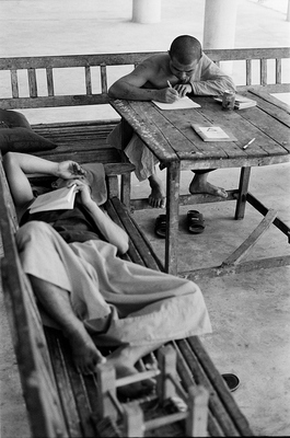 Under the shade of a large temple two monks are studying, well, one is actually sleeping. Right next to them were a few small chairs and a blackboard setup, so the children of the village can also study.

Throughout Asia, this is fairly typical, monks teaching the children, while they are studying themselves.