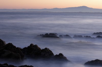 The sun rises over the Pacific ocean seen from the Monterey peninsula. Looking back towards the main land, the sun is still below the horizon. A very long exposure has rendered the waves of the ocean like mist hanging in the mountains.
It is images like these that make getting up well before first light worth it and rewarding.